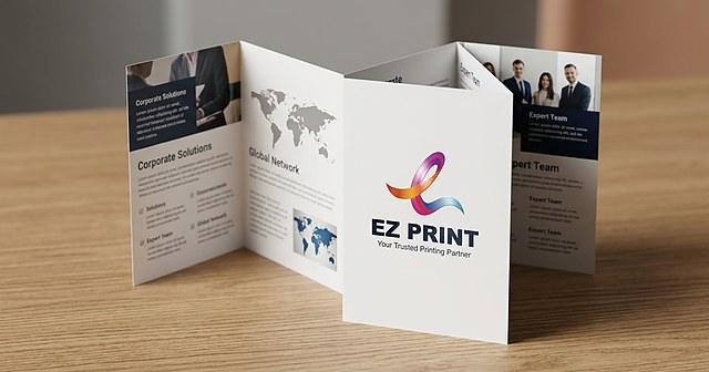 Illustration of three blank folded brochures, a tri-fold, a Z fold and a closed leaflet, on a dark wooden desk.
